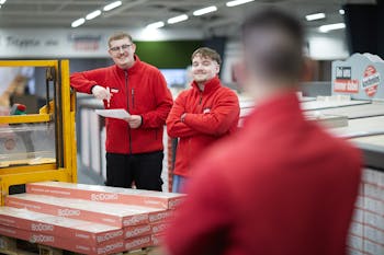 Drei Auszubildende vom LaminatDEPOT stehen in der Filiale neben einem Gabelstapler