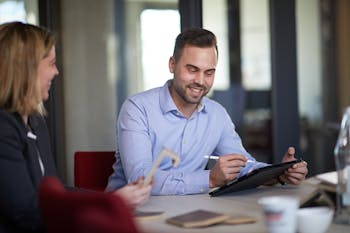 Mann hält Tablet in der Hand und sitzt neben Frau mit Treppenkante in der Hand